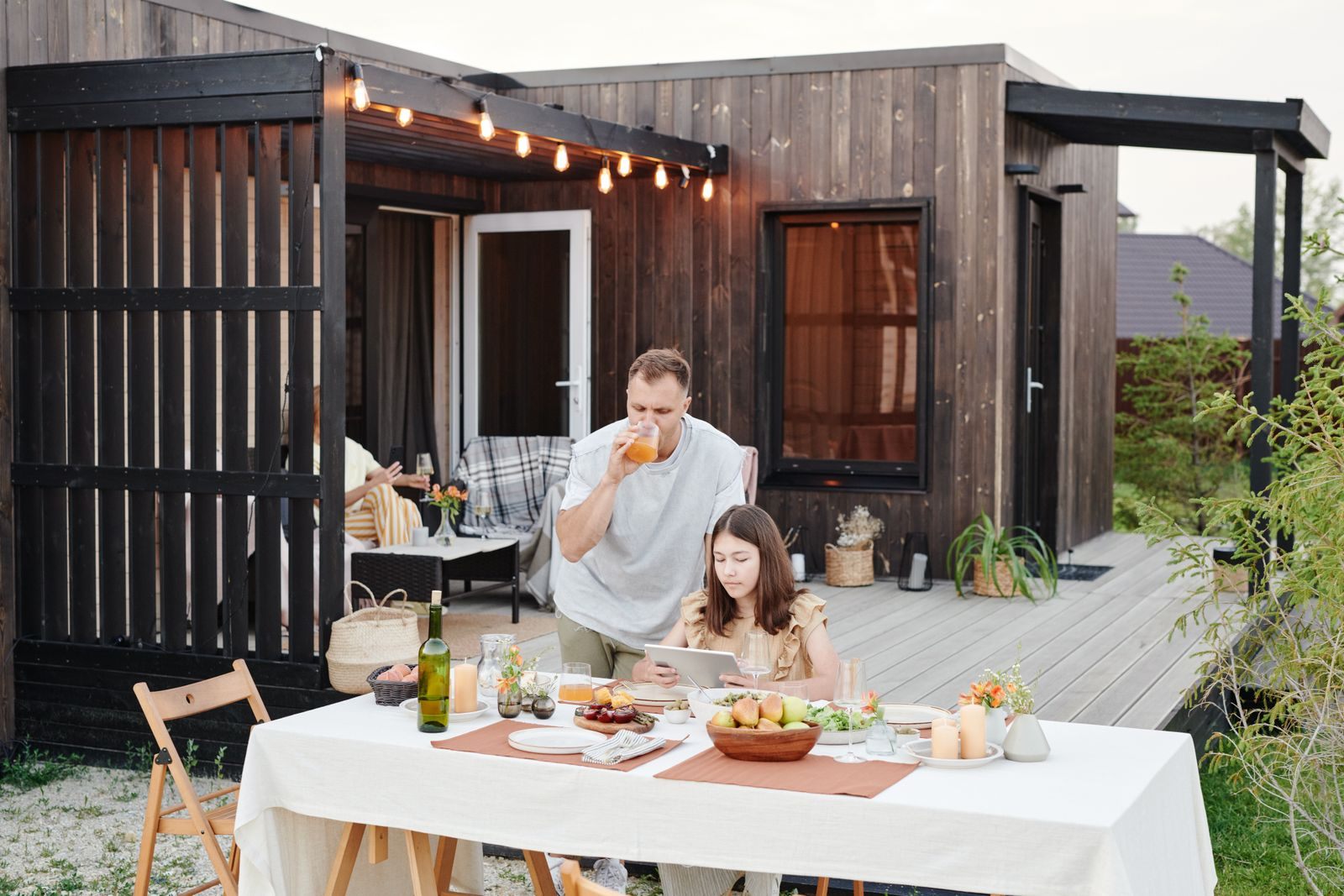 Couple sharing a meal at an outdoor table on the deck of a small wooden cabin, one of many staycation ideas for couples