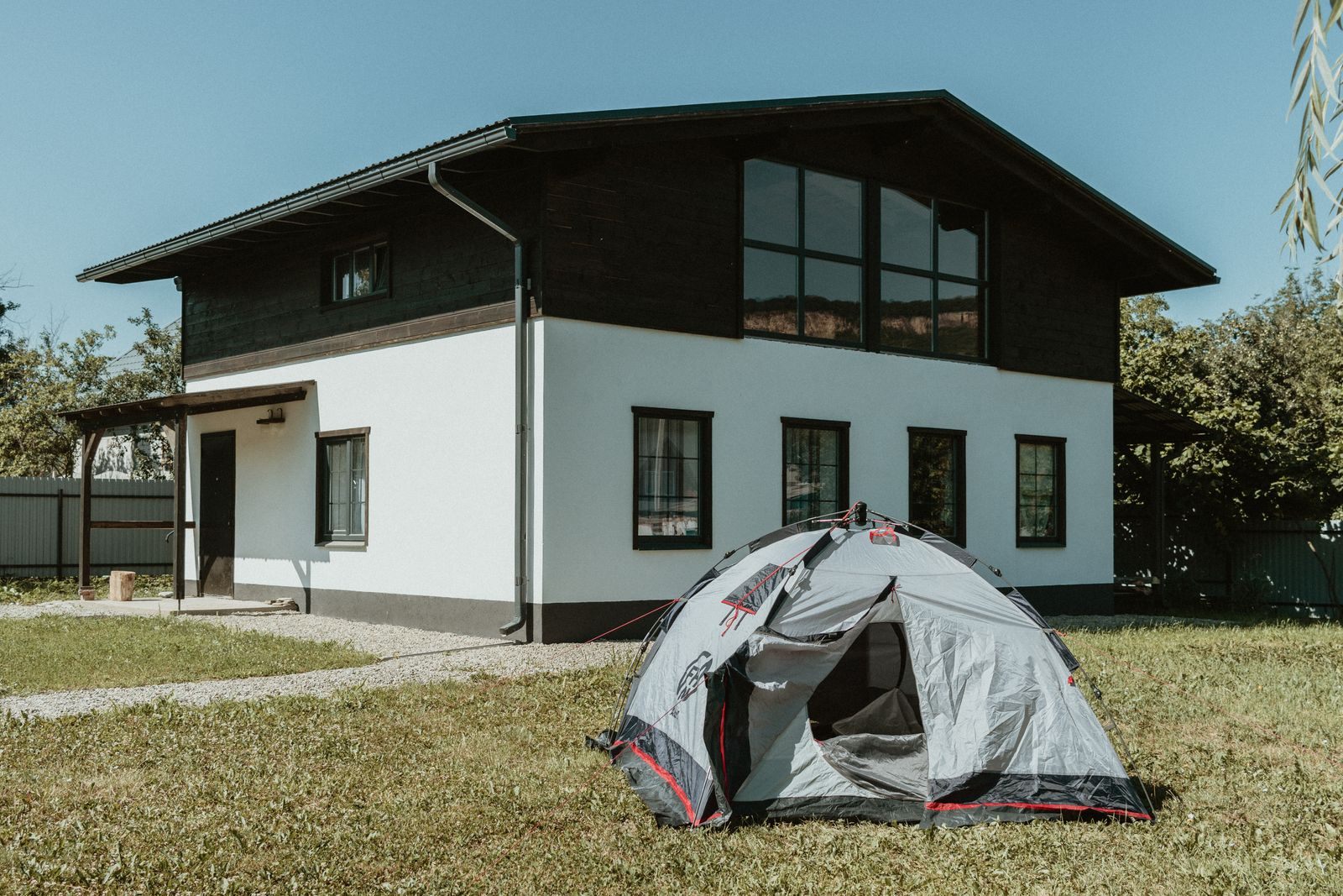 Camping tent pitched on the lawn in front of a two-story house, an easy staycation idea at home